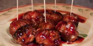 Meatballs with sauce and toothpicks on plate.