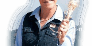 Woman holding wheat, wearing sunglasses and cap.