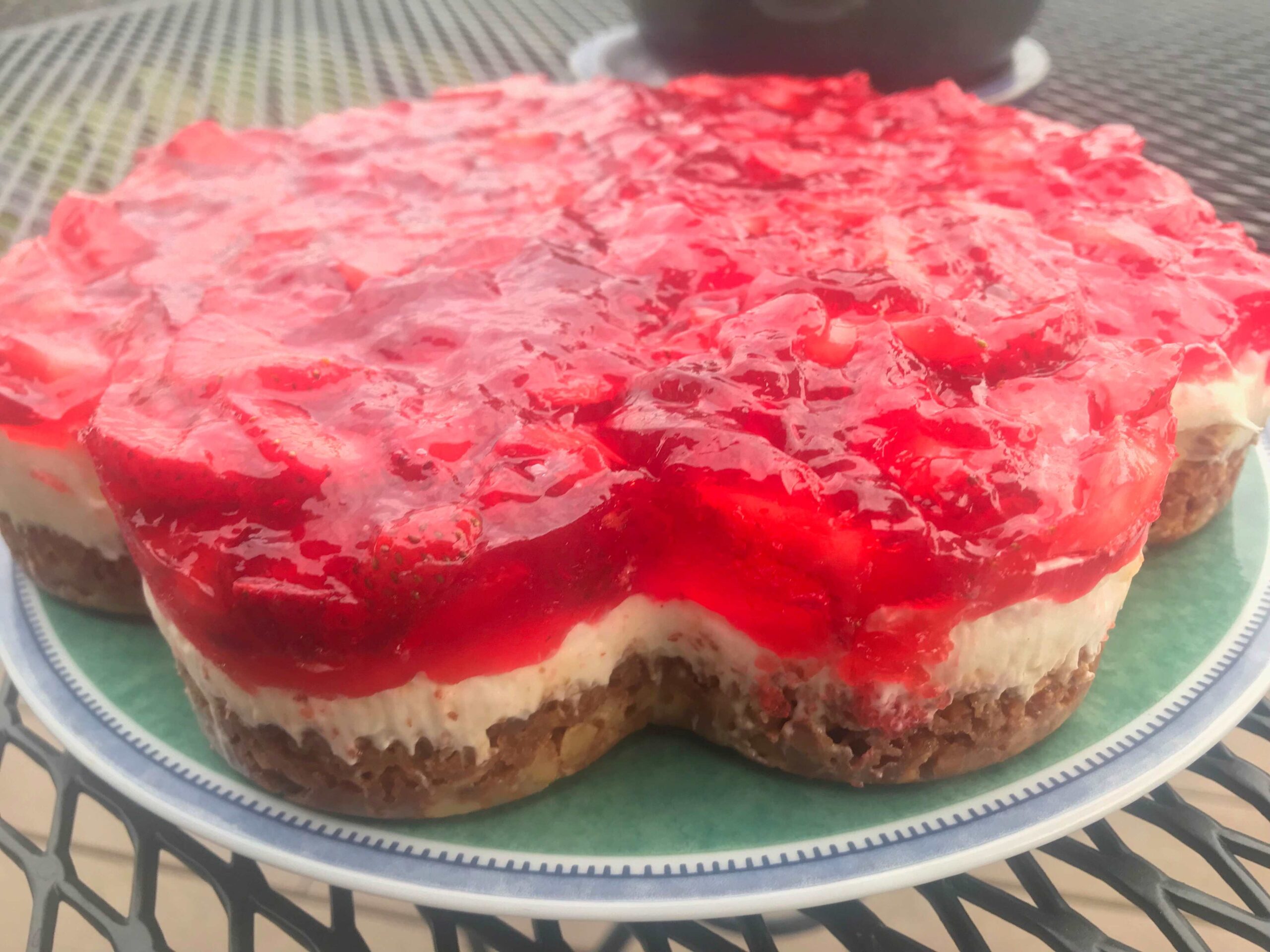 Strawberry cheesecake with a glossy red topping on a green plate.