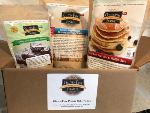 Three pancake and waffle mixes with a recipe card on a wooden surface.