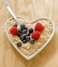 Heart-shaped bowl of oatmeal topped with fresh blueberries and raspberries.