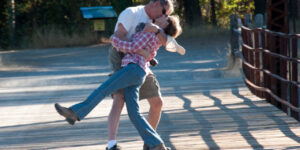 A couple dancing joyfully outdoors on a sunny day.