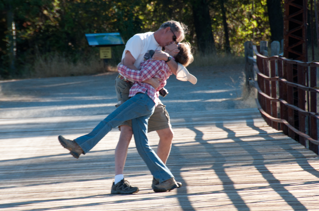 A couple dancing joyfully outdoors on a sunny day.