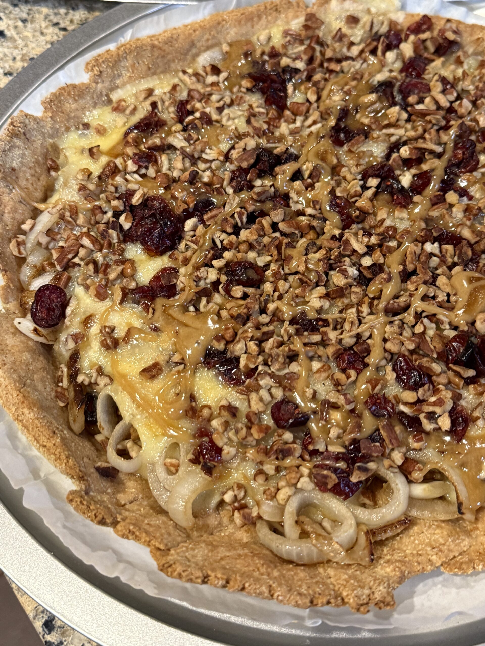 Close-up of a pecan-topped dessert pizza with a golden crust.